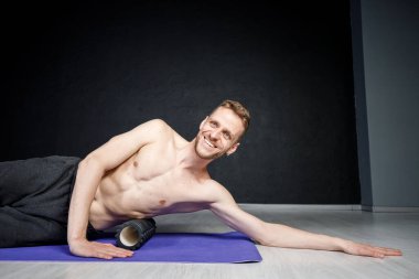 Genç atletik adam omurga kaslarını bigudiyle çalıştırıyor..