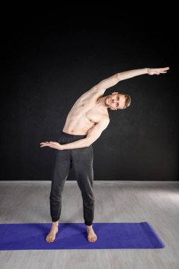 Genç adam ısınma egzersizleri yapıyor, omurga kaslarını esnetiyor..