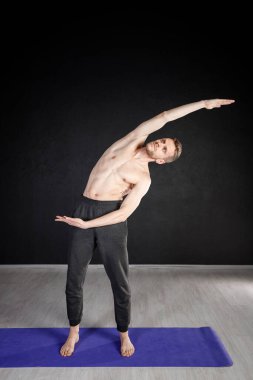 Genç adam ısınma egzersizleri yapıyor, omurga kaslarını esnetiyor..