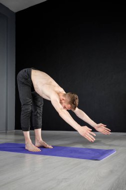 Genç atletik adam sırtını güçlendirmek ve bacak kaslarını germek için 