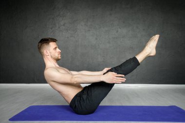 Genç, atletik adam yoga minderinde karın kası egzersizi yapıyor..