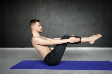 Genç, atletik adam yoga minderinde karın kası egzersizi yapıyor..