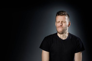 Siyah arka planda acı dolu, diş ağrısı çeken genç bir adam..