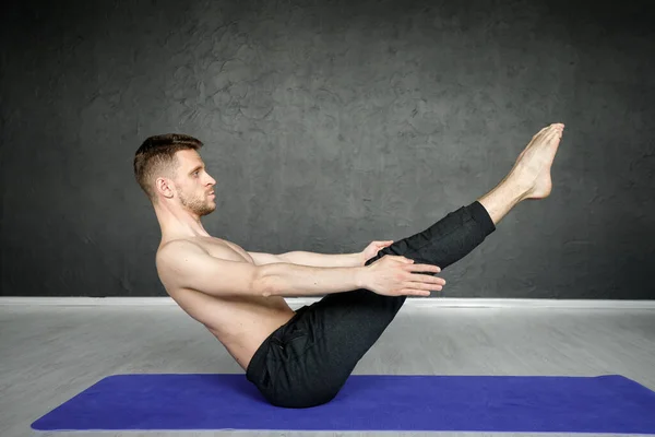 Genç, atletik adam yoga minderinde karın kası egzersizi yapıyor..
