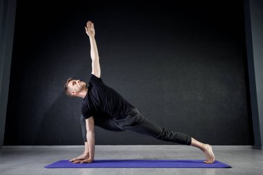 Spor salonundaki yoga minderinde bacak esnetme egzersizi yapan genç bir adam. Yoga pozisyonları üzerinde çalışıyorum..