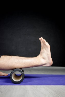 Genç atletik adam yoga oyuncusunun yardımıyla bacak esneme hareketleri yapıyor..