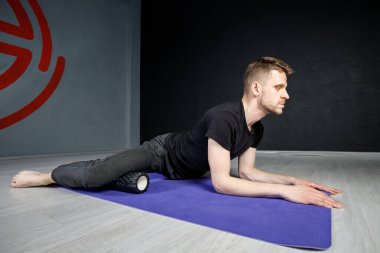 Genç atletik adam, iç kalça kaslarını esnetme egzersizi yapıyor..