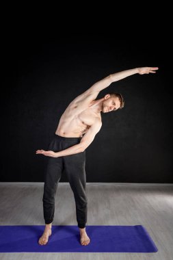 Genç adam ısınma egzersizleri yapıyor, omurga kaslarını esnetiyor..