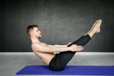 Genç, atletik adam yoga minderinde karın kası egzersizi yapıyor..