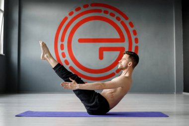 Genç, atletik adam yoga minderinde karın kası egzersizi yapıyor..