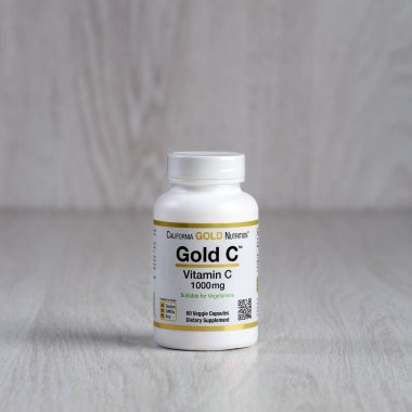 Kamyanets-Podilskyi, Ukrayna - 27 Haziran 2020: Kamyanets-Podilskyi, Ukrayna - 27 Haziran 2020: California Gold Nutrition, Gold C, C vitamini, 1000 mg. Hafif ahşap arka planda haplarla dolu bir şişe.