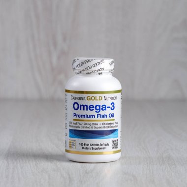 Kamyanets-Podilskyi, Ukrayna - 27 Haziran 2020: Kaliforniya Altın Beslenme, Omega-3, Premium Balık Yağı. Hafif ahşap arka planda haplarla dolu bir şişe.