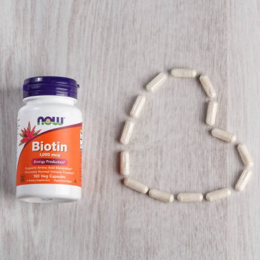 Kamyanets-Podilskyi, Ukrayna - Kasım 04, 2019: Now Foods, Biotin, 1,000 mcg, 100 Veg Capsules. Hafif ahşap arka planda haplarla dolu bir şişe.