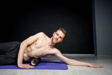  Genç atletik adam omurga kaslarını bigudiyle çalıştırıyor..