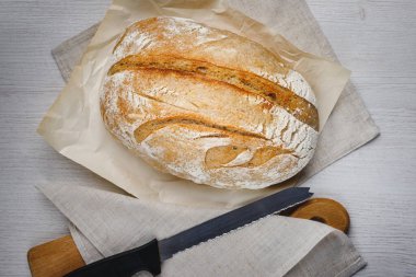 Taze pişmiş tartin ekmek ve tahta bir tahtanın üzerinde bıçak. Üst görünüm.