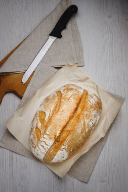 Taze pişmiş tartin ekmek ve tahta bir tahtanın üzerinde bıçak. Üst görünüm.