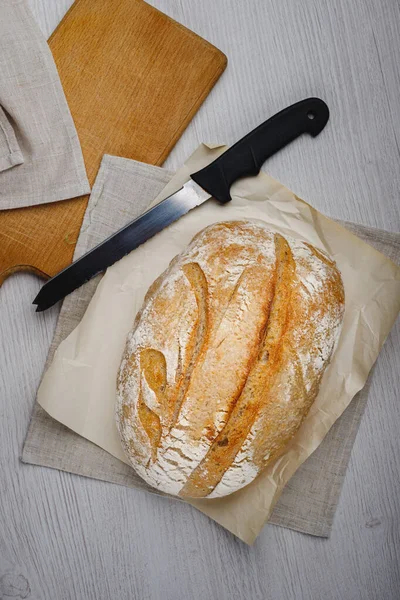 Taze pişmiş tartin ekmek ve tahta bir tahtanın üzerinde bıçak. Üst görünüm.