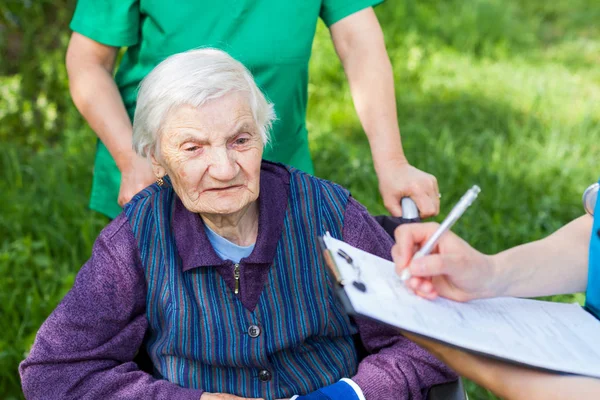 Пожилая Больная Женщина Инвалидной Коляске Медицинские Сестры Обсуждают Лечение Открытом — стоковое фото
