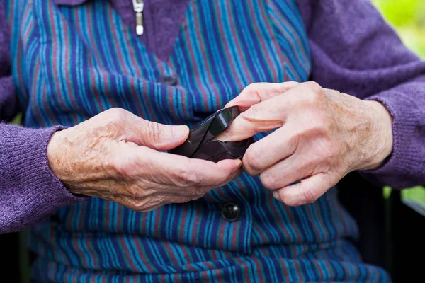 Close up picture of old woman's hands holding pulse oximeter on fingertip outdoor