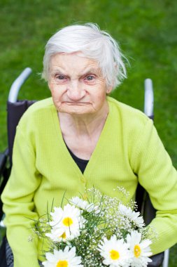 Yaşlı kadın tekerlekli sandalyede oturan bir çiçek buketi Doğum günü için alma devre dışı