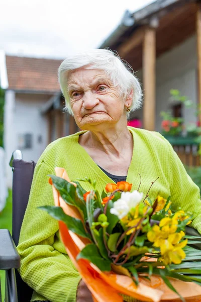 彼女の誕生日の花の花束を受け取った 車いす 高齢者の女性を無効に — ストック写真
