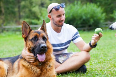 Alman çoban köpeği ile oynarken mutlu bir adam resmi