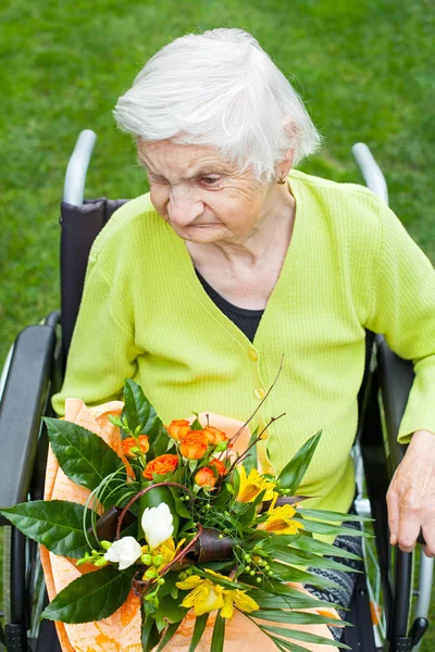 彼女の誕生日の花の花束を受け取った 車いす 高齢者の女性を無効に — ストック写真