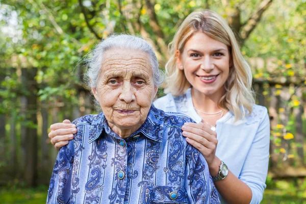 Lächelnder Junger Hausmeister Spaziert Mit Seniorin Garten — Stockfoto