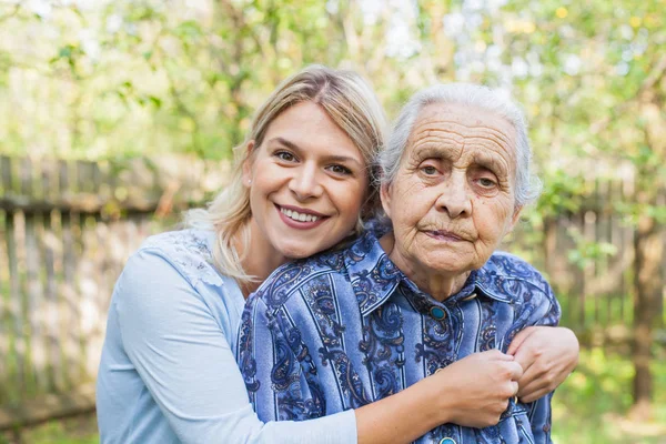stock image Young cheerful woman hugging her sick grandmother outdoor