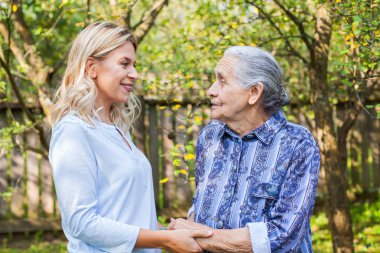 Yaşlı kadın bahçede - tıbbi bakım ile yürüme dostu caregiver