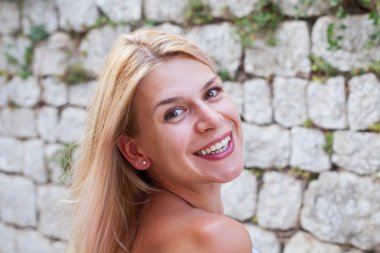 Taş duvar önünde güzel bir gülümseyen genç bayan portresi kapatın