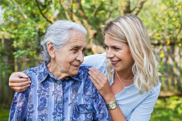 Lächelnder Junger Hausmeister Spaziert Mit Seniorin Garten — Stockfoto