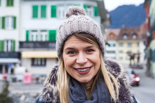 Cheerful female tourist smiling to the camera in the city of Interlaken, swiss alps