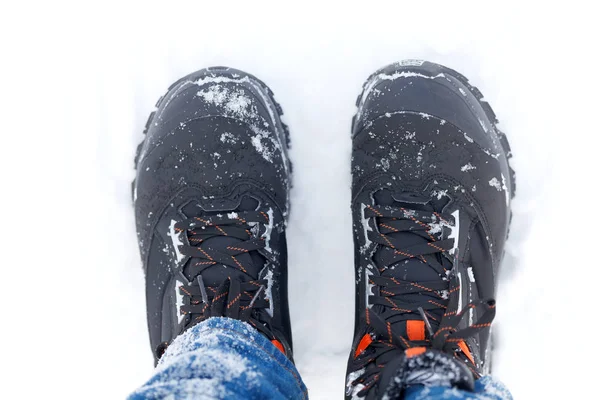 Picture of a man\'s feet in boots standing in the snow