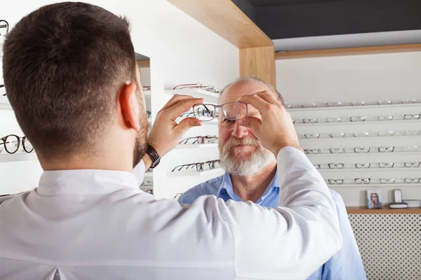 Joven Óptico Ayudando Los Clientes Masculinos Mayores Elegir Gafas Tienda — Foto de Stock