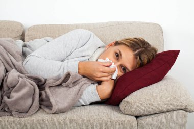 Burnunu - sinüs enfeksiyonu üfleme kanepede yatan hasta bir kadın