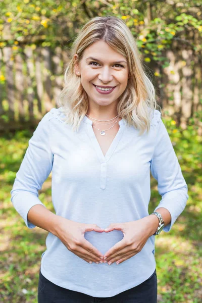 Těhotná Šťastná Žena Ukazuje Symbol Srdce Před Její Bříško — Stock fotografie