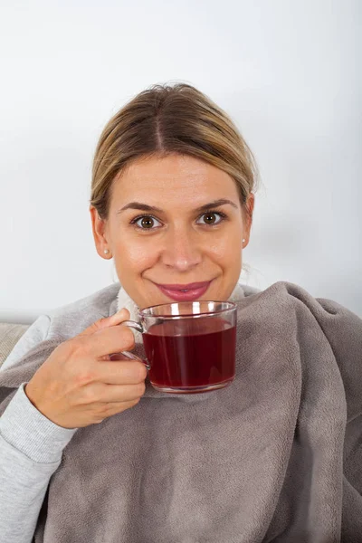 熱いお茶を飲むと ナプキンを保持しながらソファで休んで病気の若い女性 — ストック写真