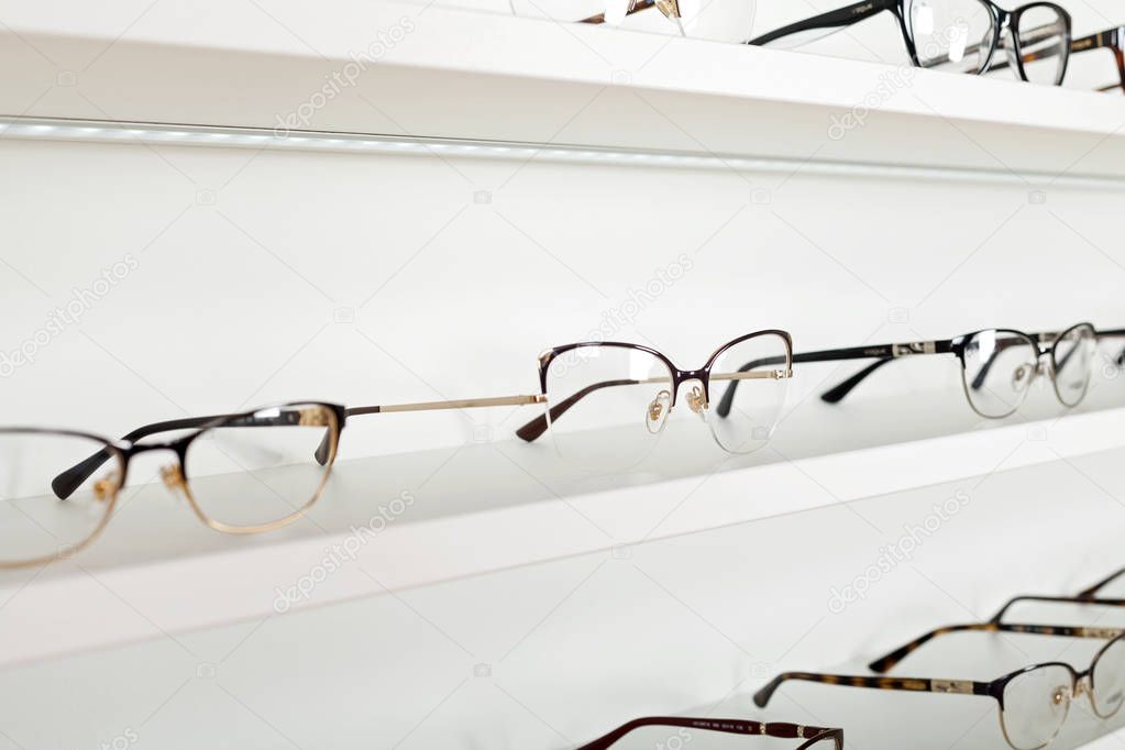 Fashionable corrective eye glasses on a shelf in optical store