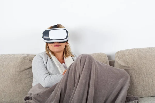 Woman watching a 3d virtual reality video with headset while relaxing on the sofa