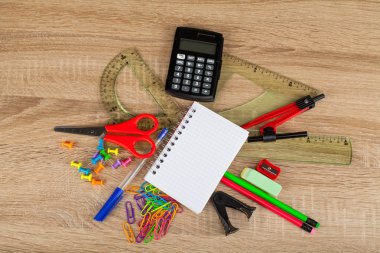 Öğrenme araçları - defter, kalem, makas, hesap makinesi, cetvel, vb - ahşap arka plan üzerinde okul