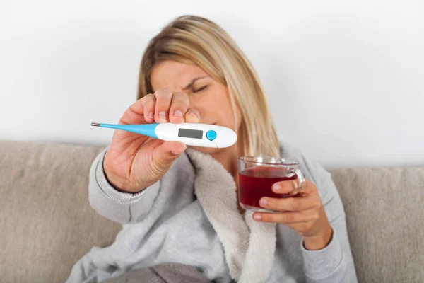 Sick Blonde Woman Sitting Couch Holding Cup Hot Tea Thermometer — Stock Photo, Image