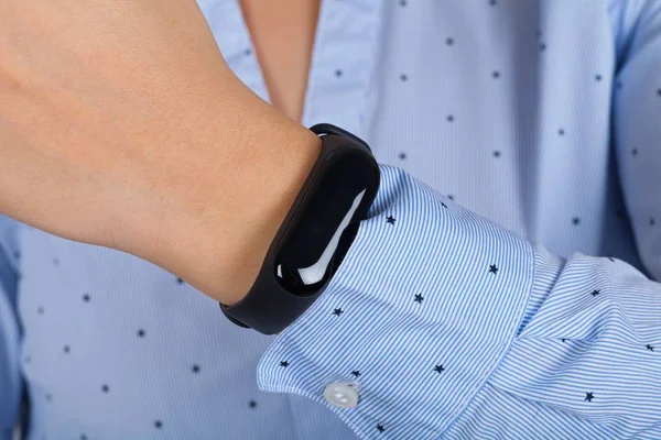 Close up picture of young female wearing mi fit band, checking her pluse & steps for the day