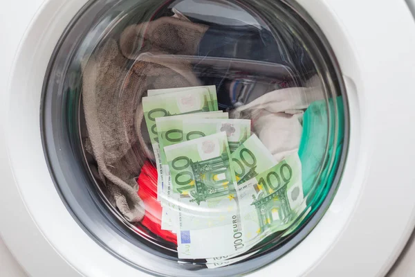 Money in the washing machine loaded with laundry - Euro currency