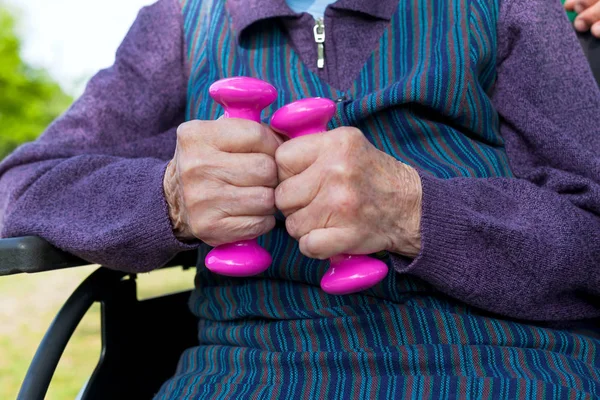 障害高齢者の女性 車椅子に座っている彼女のしわだらけの手でダンベルを保持 — ストック写真