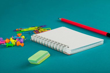 Beyaz defter, kalem ve renkli kağıt kırpmak üstünde mavi arka plan - okul kavramı malzemeleri