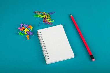 Beyaz defter, kalem ve renkli kağıt kırpmak üstünde mavi arka plan - okul kavramı malzemeleri