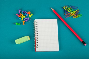 Beyaz defter, kalem ve renkli kağıt kırpmak üstünde mavi arka plan - okul kavramı malzemeleri