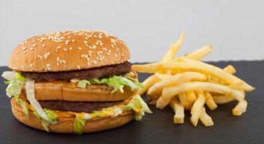 Sığır eti, çedar, susam çörek içinde marul ile lezzetli bir duble çizburger resmini kapatın 