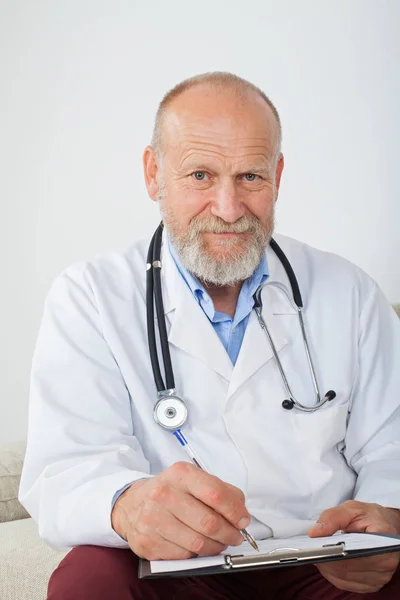 Médico Sênior Bem Sucedido Preenchendo Formulário Diagnóstico Médico Sentado Sofá — Fotografia de Stock